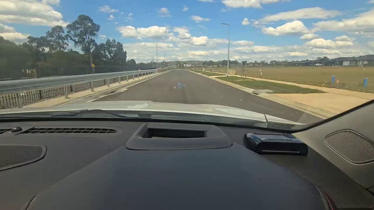 The Aura on the dash, looking down a road lined with gum trees.
